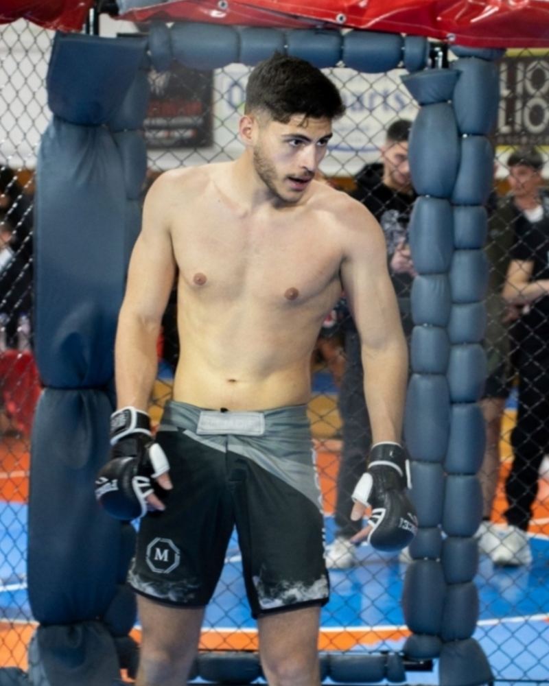 Miliadis Nikos standing in the cage with gloves on